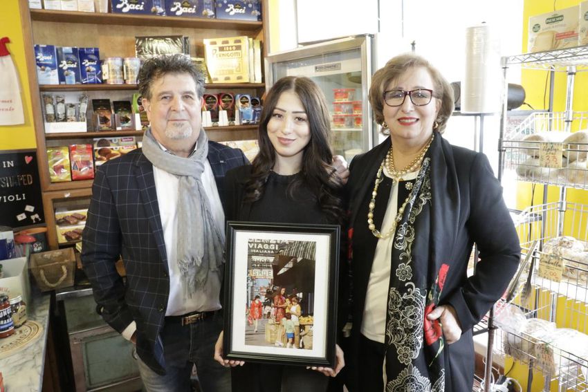 Mary and Nick Pascale and their daughter Cinzia hold a framed copy of the photo taken by Bob Olsen in 1970. They're pictured at the grocery store they own, Pascale Gourmet.