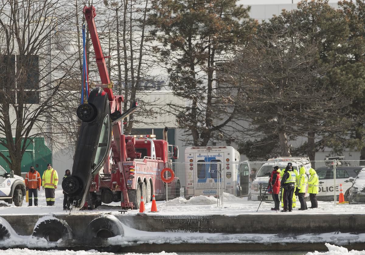A car is pulled from the western channel metres away from the ferry to Billy Bishop Airport. One body was pulled earlier from the wreckage before the car was lifted out.