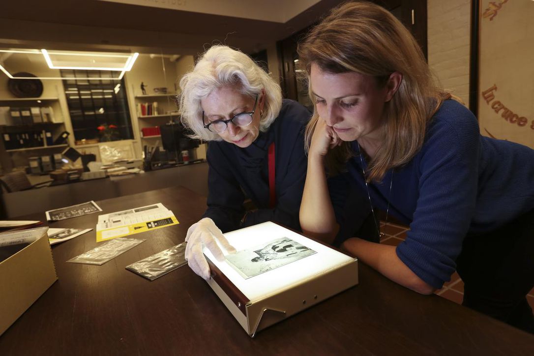 Trinity archivist Sylvia Lassam, left, and communications co-ordinator Sarah Kidd examine one of the original glass negatives of Reginald Wilkins.