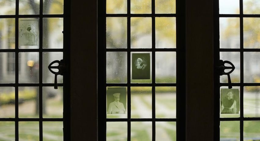 Adhesive reproductions of old photo negatives are attached to the windows overlooking a courtyard at U of T's Trinity College. The college's archives hold 210 glass-plate negatives of portraits from The War Memorial Volume of Trinity College, about 543 students and alumni who had served in the First World War.