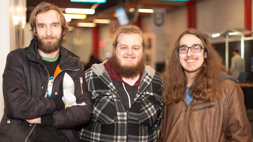 Une photo de trois jeunes hommes qui sourient.