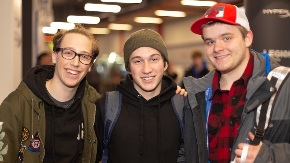 Trois jeunes hommes sourient pour la photo.